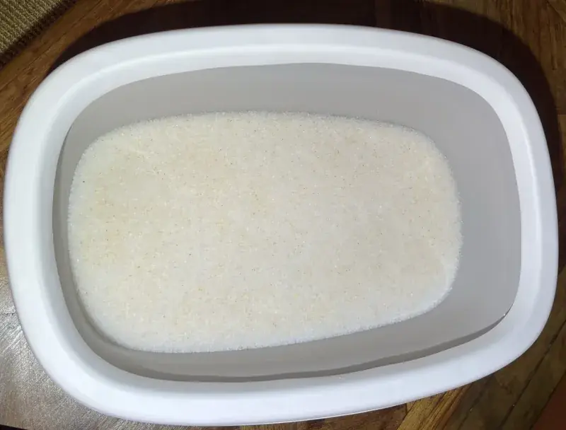 Un bac &agrave; liti&egrave;re rempli de cristaux de gel de silice blancs et propres, sur un parquet en bois