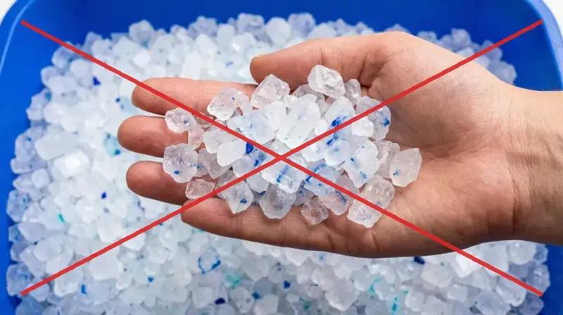 Main tenant de gros cristaux de silice anguleux et tranchants, barr&eacute;s d'une croix rouge &mdash; le type de cristaux que Pacha n'utilise pas